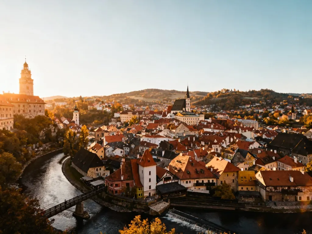 Malownicza panorama europejskiego miasteczka w dolinie z rzeką i tradycyjną zabudową w świetle zachodzącego słońca.